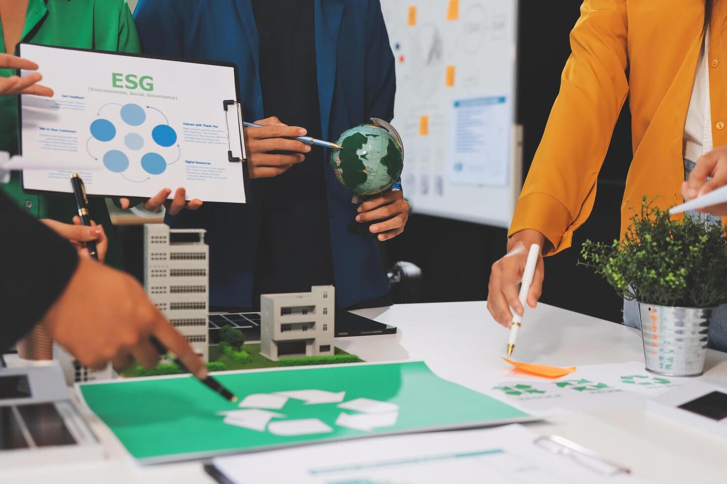 People working together on a table with a green building photo