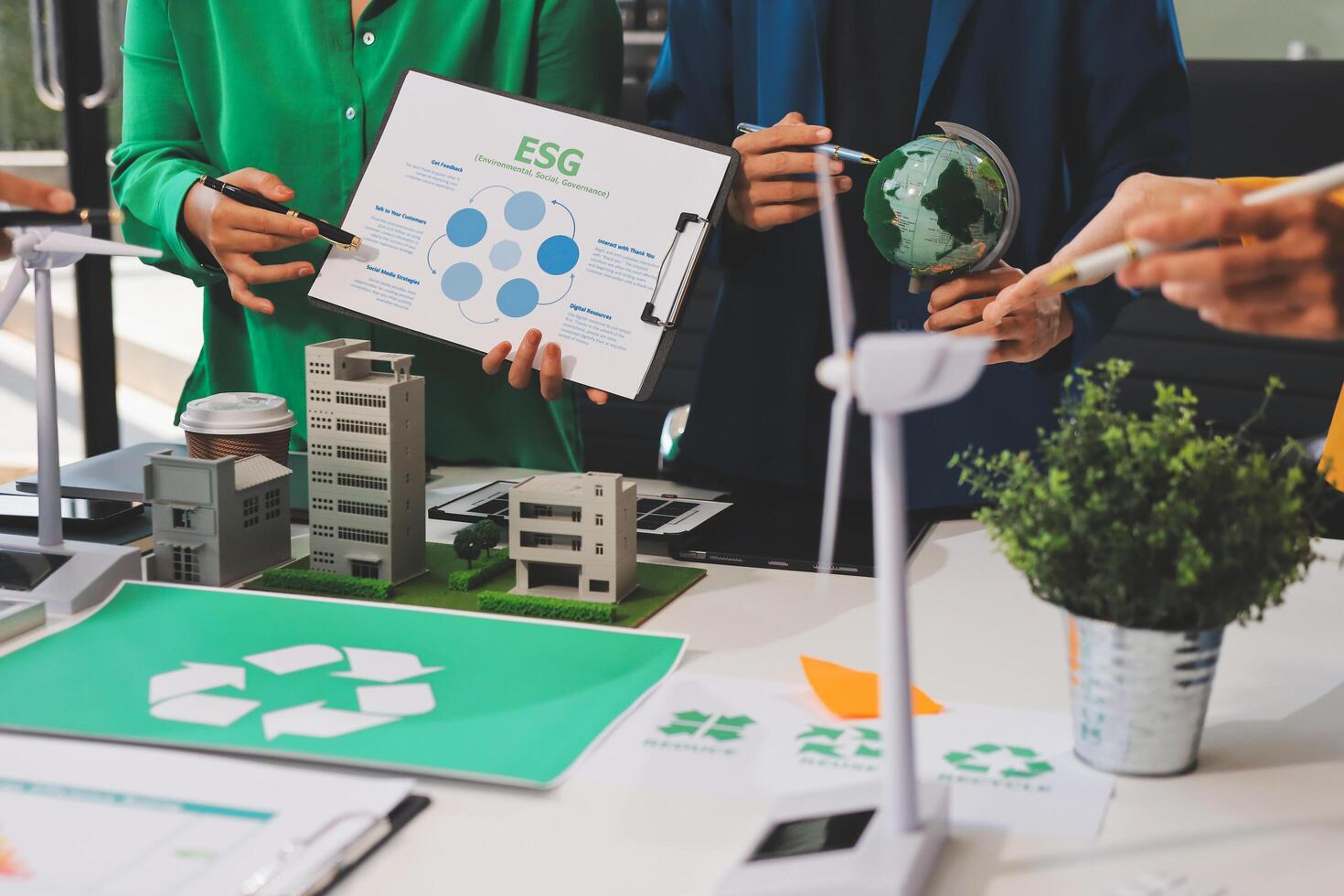 A group of people are standing around a table with a green recycling symbol photo