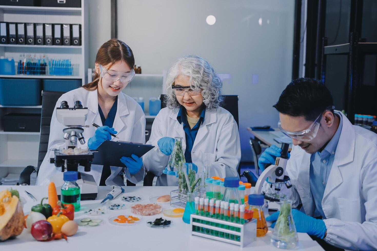 Three people in lab coats looking at a tablet photo