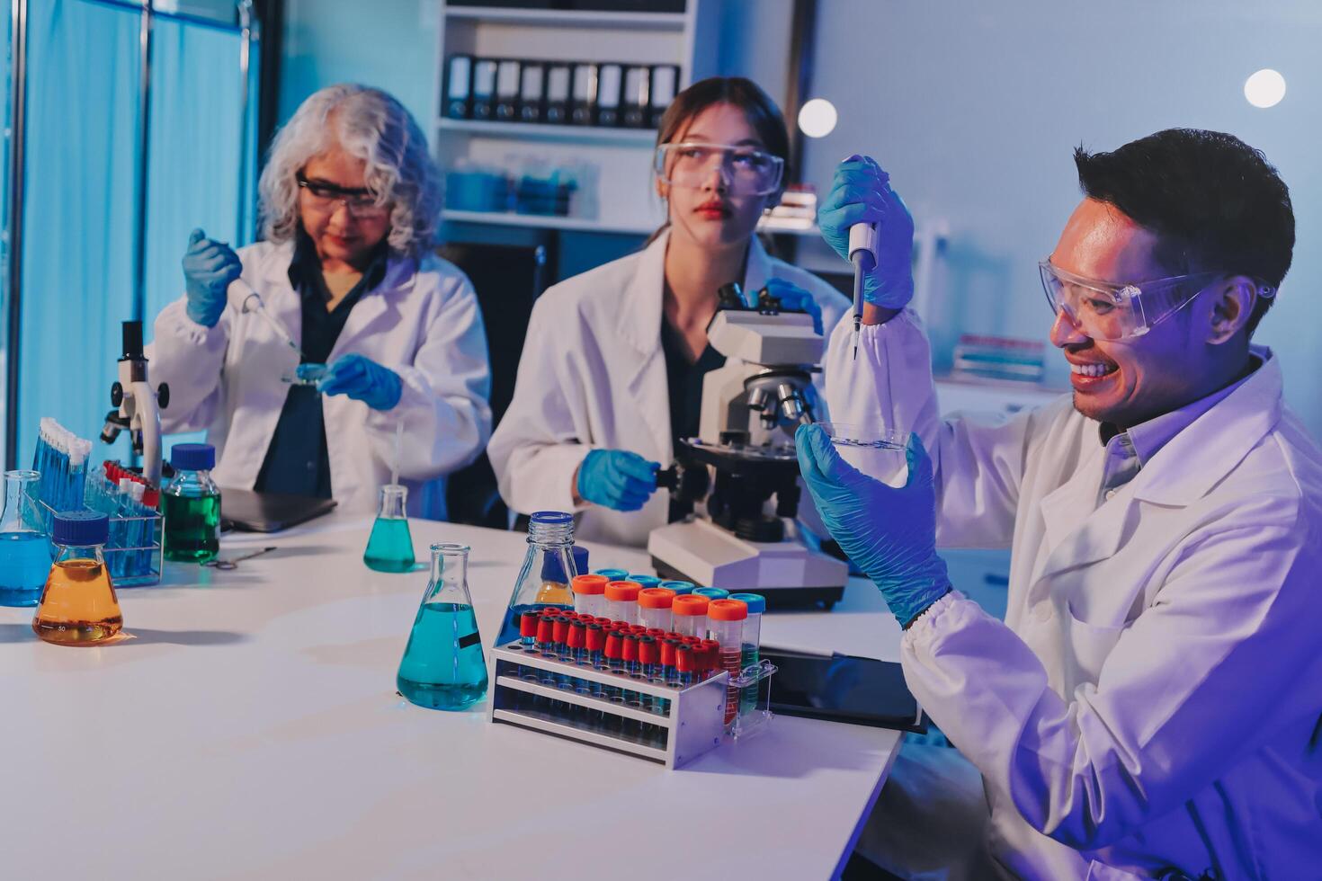 Three people in lab coats working on something photo