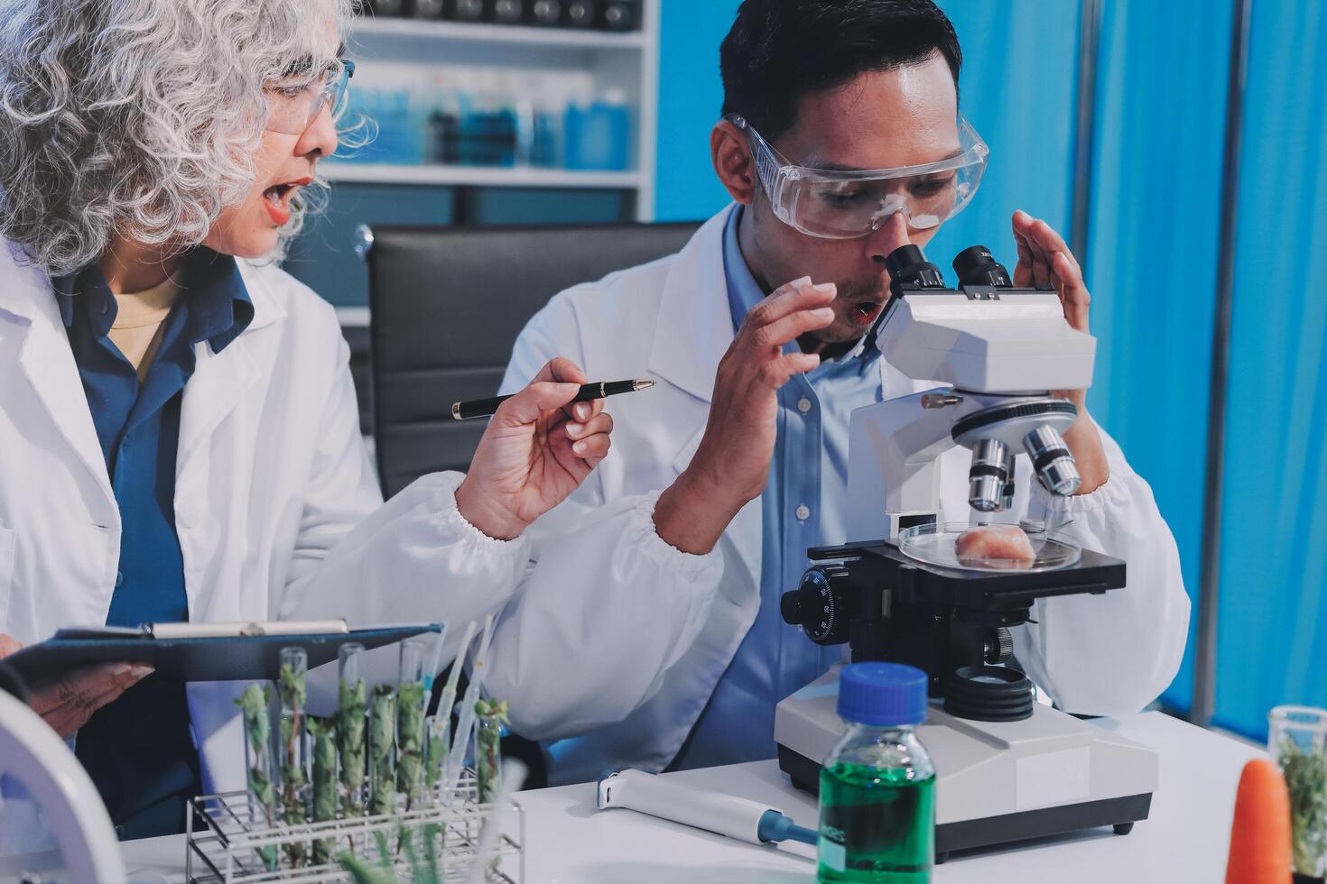 Two people in lab coats looking at something on a microscope photo
