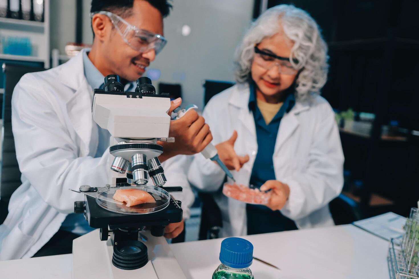 Two people in lab coats looking at something through a microscope photo