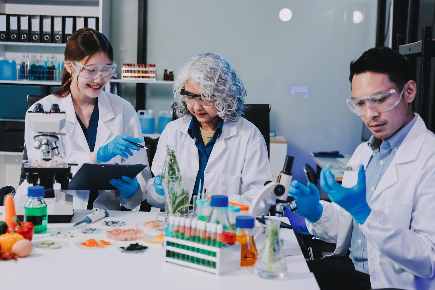 Three people in lab coats working on a tablet photo