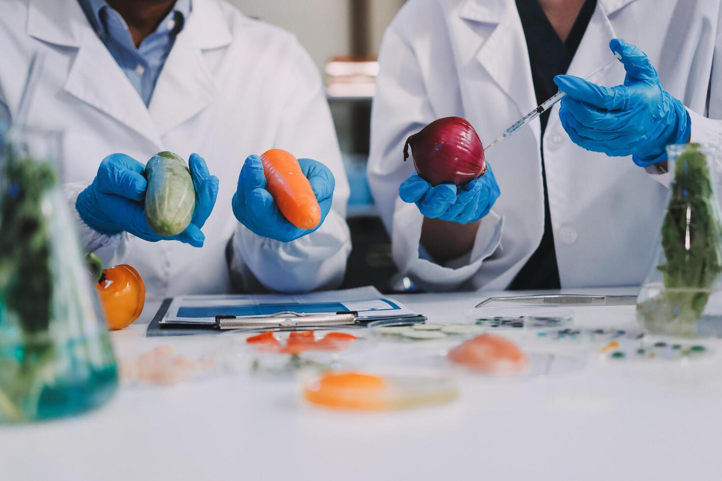 Two people in lab coats holding up vegetables photo