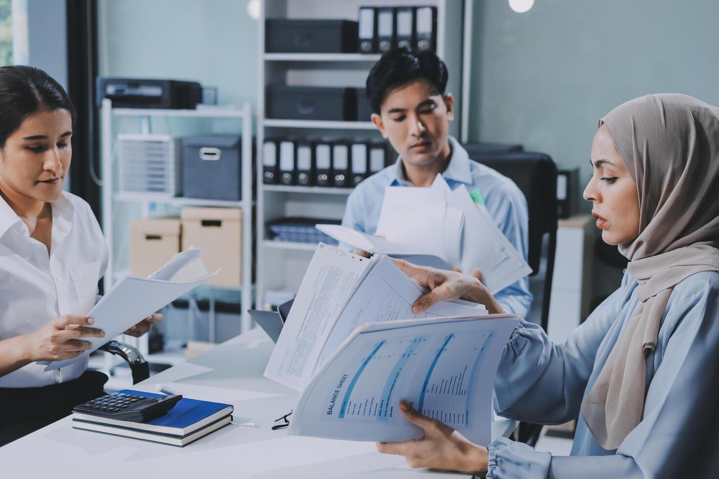 Three people in an office discussing paperwork photo