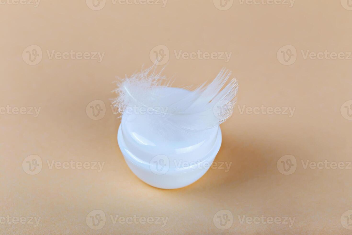 Mockup. Cream jar with feather on pastel background symbolizing soft skincare. Cream conveys luxury skincare concept. Beauty routine represented by gentle cream texture. Cosmetic elegance concept photo