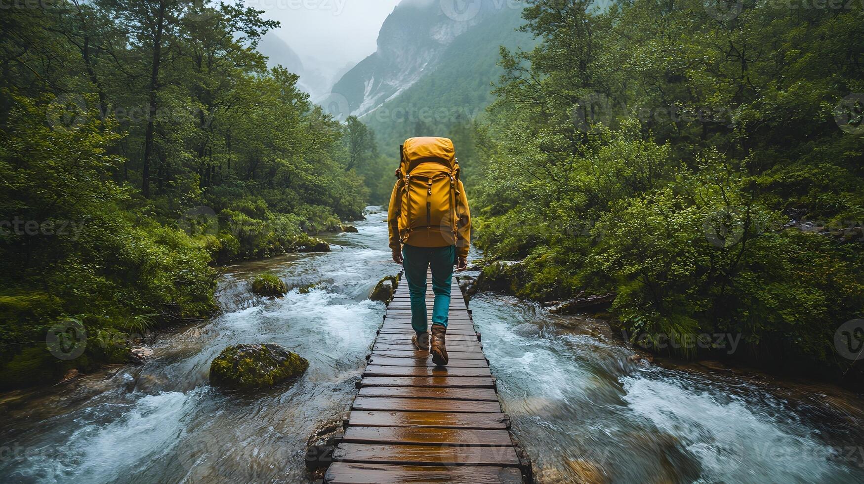 Hiker crossing a wooden bridge over a rushing mountain river, surrounded by dense green forest photo
