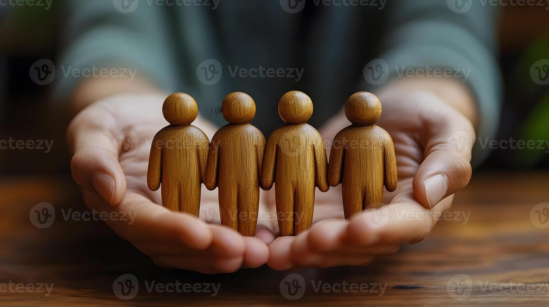 Hands gently covering wooden people models symbolizing corporate care and teamwork photo