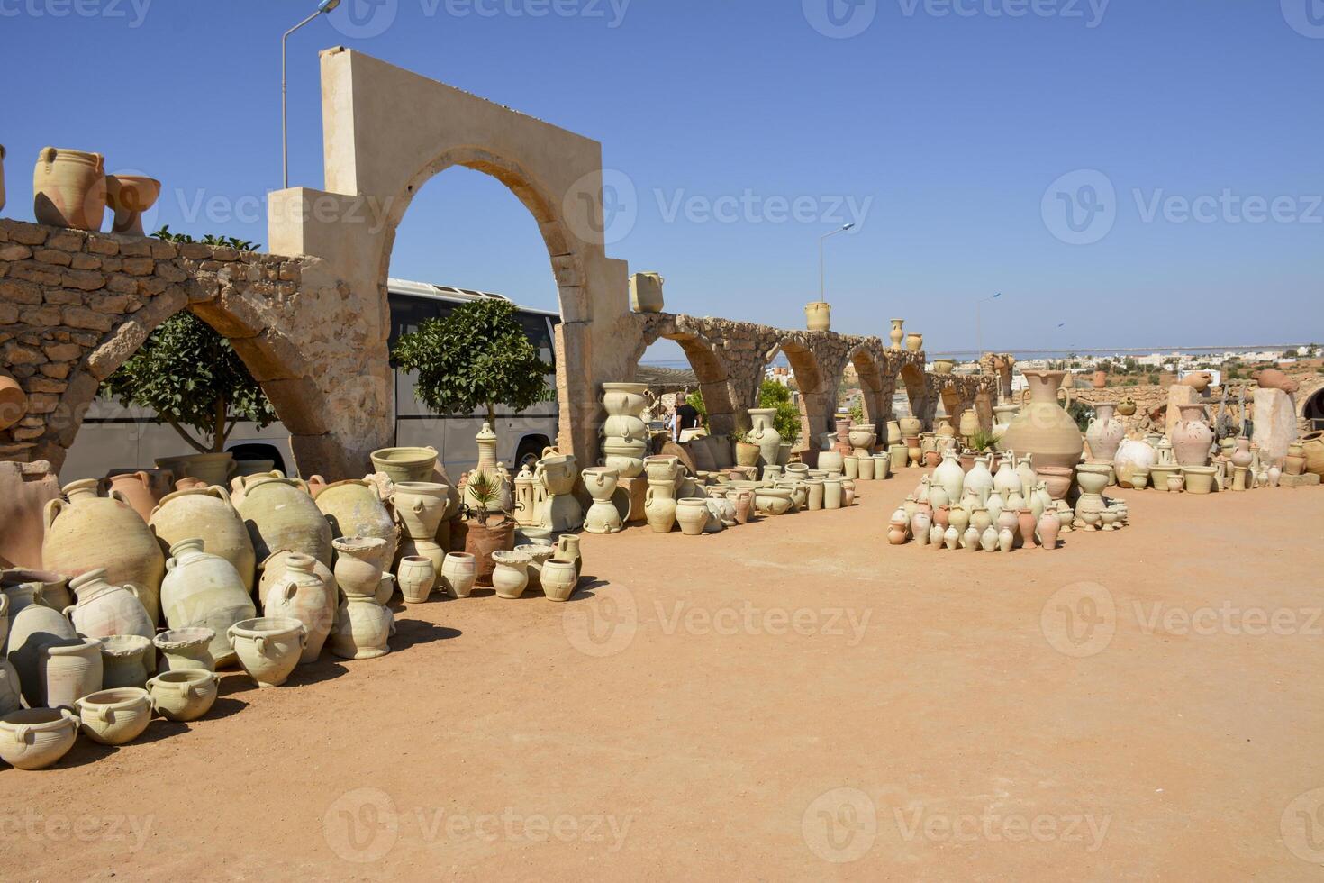 A vast array of pottery and terracotta items displayed outdoors. A pottery market in Guellala, the village of potters in Tunisia. photo