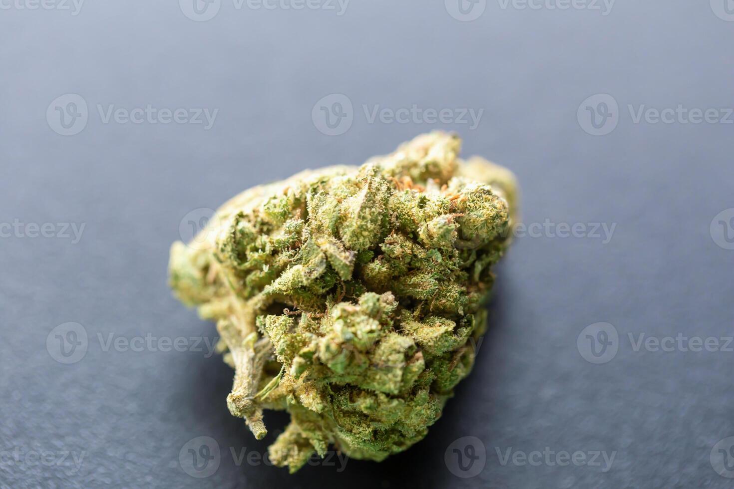 Close-up of single cannabis bud on dark background with visible trichomes and natural texture, isolated with soft lighting. Concept of medical marijuana, CBD products, or herbal wellness photo