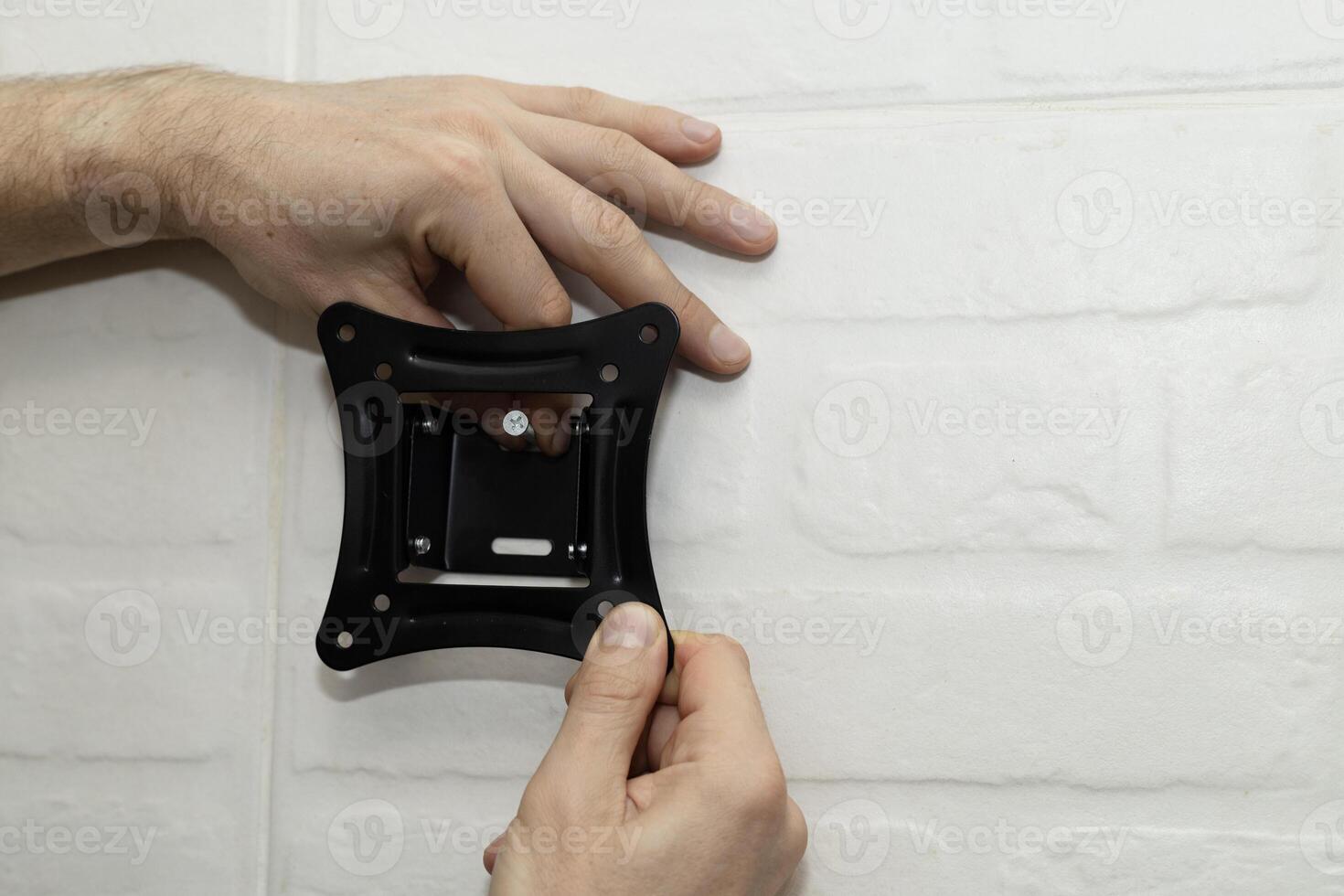 A man tries on a mount bracket and screw photo