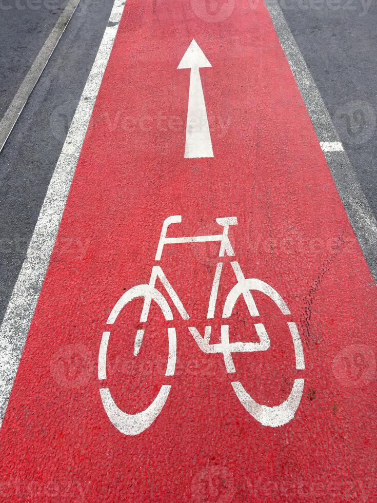 Bright red bicycle lane marking with directional arrow on urban roadway photo