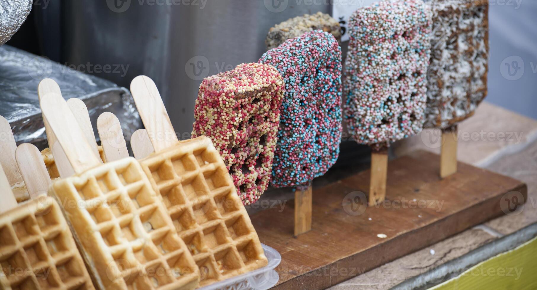 Assorted waffle and chocolate pops on sticks, arranged on a rustic wooden display photo