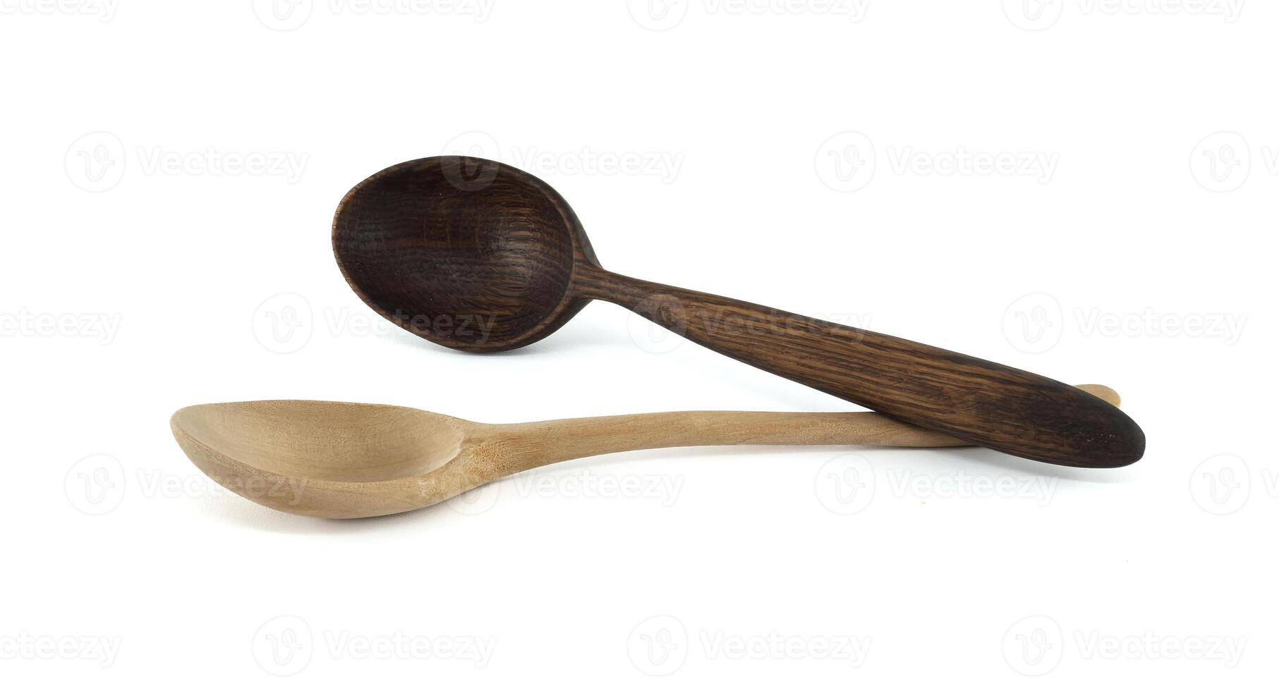 Two wooden spoons, one light and one dark, are artfully arranged on a white surface. photo