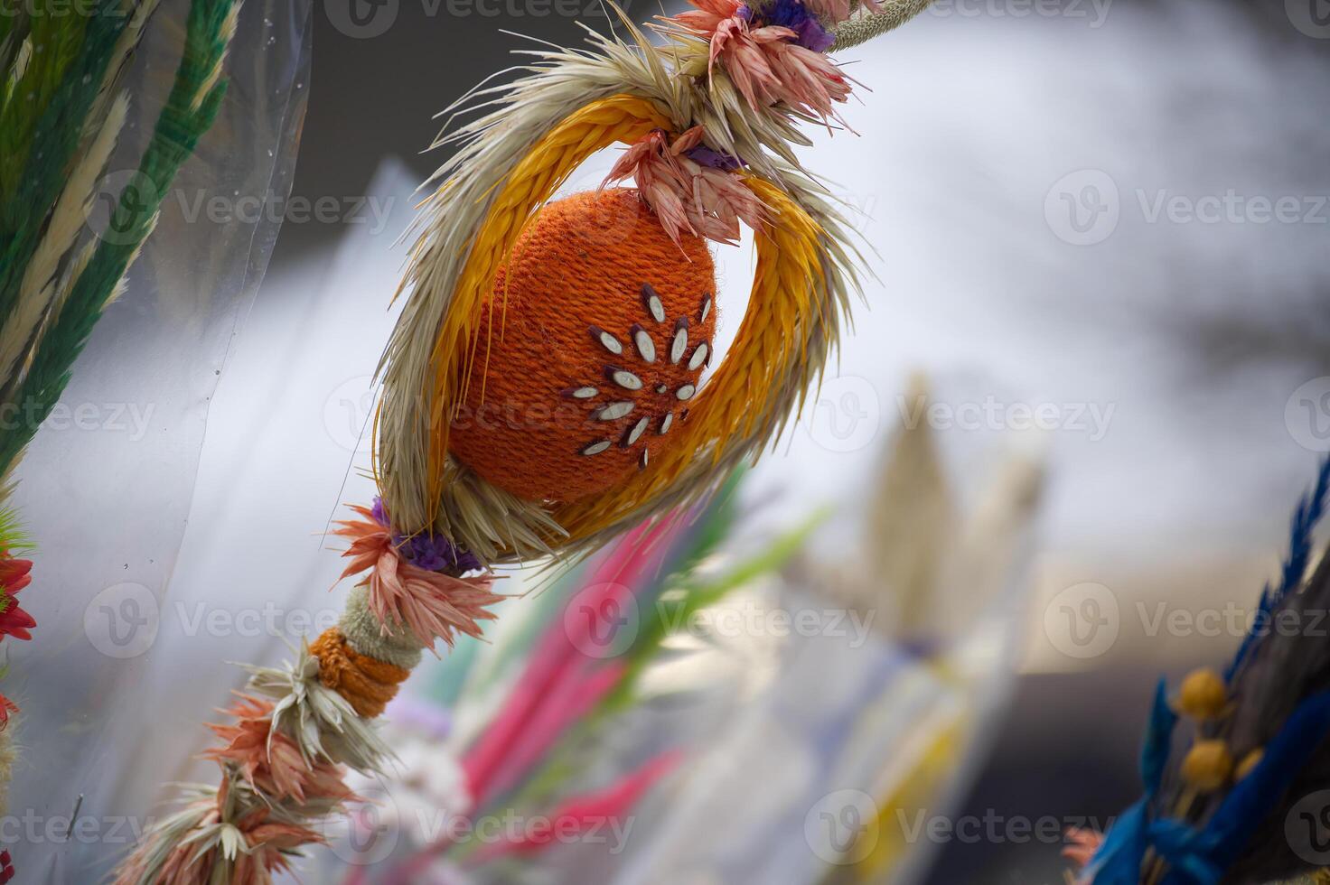 A vibrant, handmade Easter palm featuring a knitted orange egg and dried flowers, captured at a fair photo