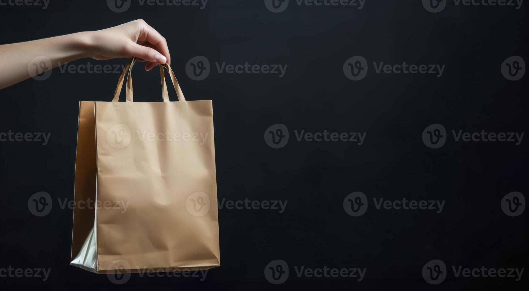 Paper shopping bag held by hand against black background with copy space photo