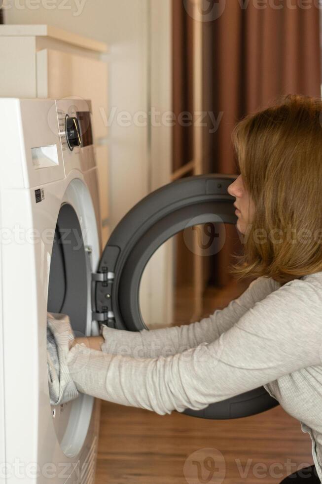 Woman loading laundry into washing machine in modern home setting during daytime photo