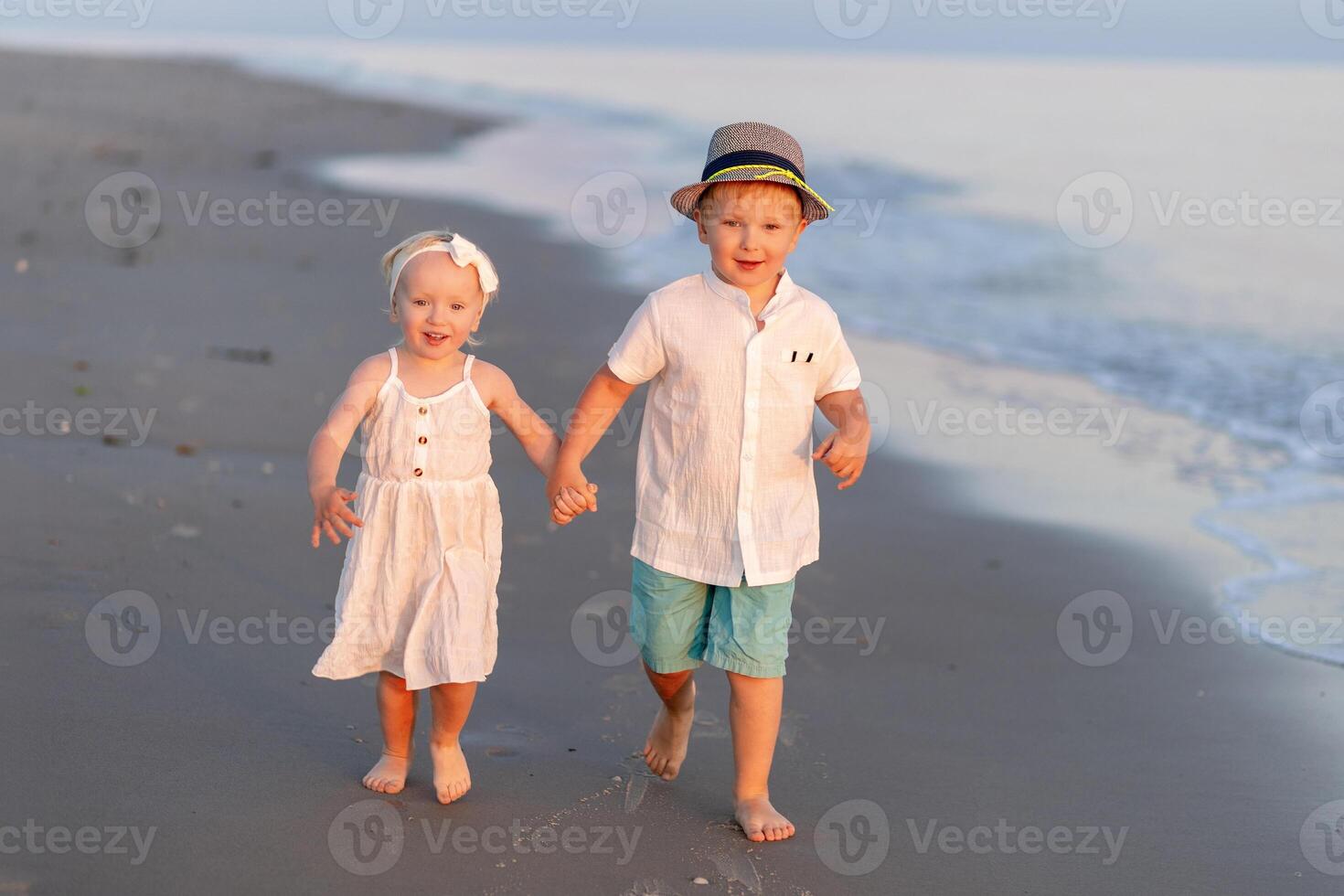 Children joyfully walk hand in hand along a serene beach at sunset near the shoreline photo