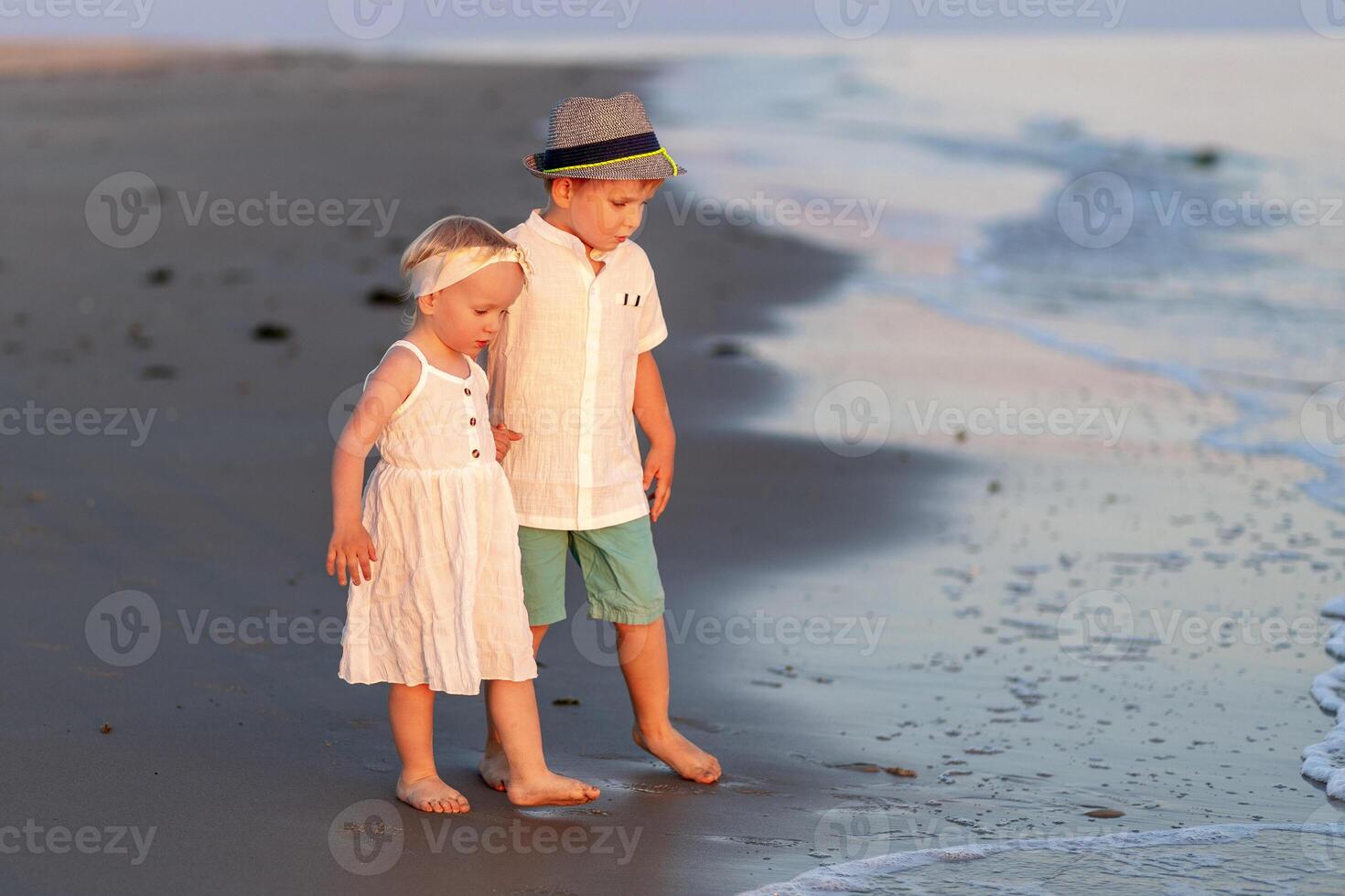 Children play at sunset on the beach, enjoying the waves and sand with joyful expressions photo