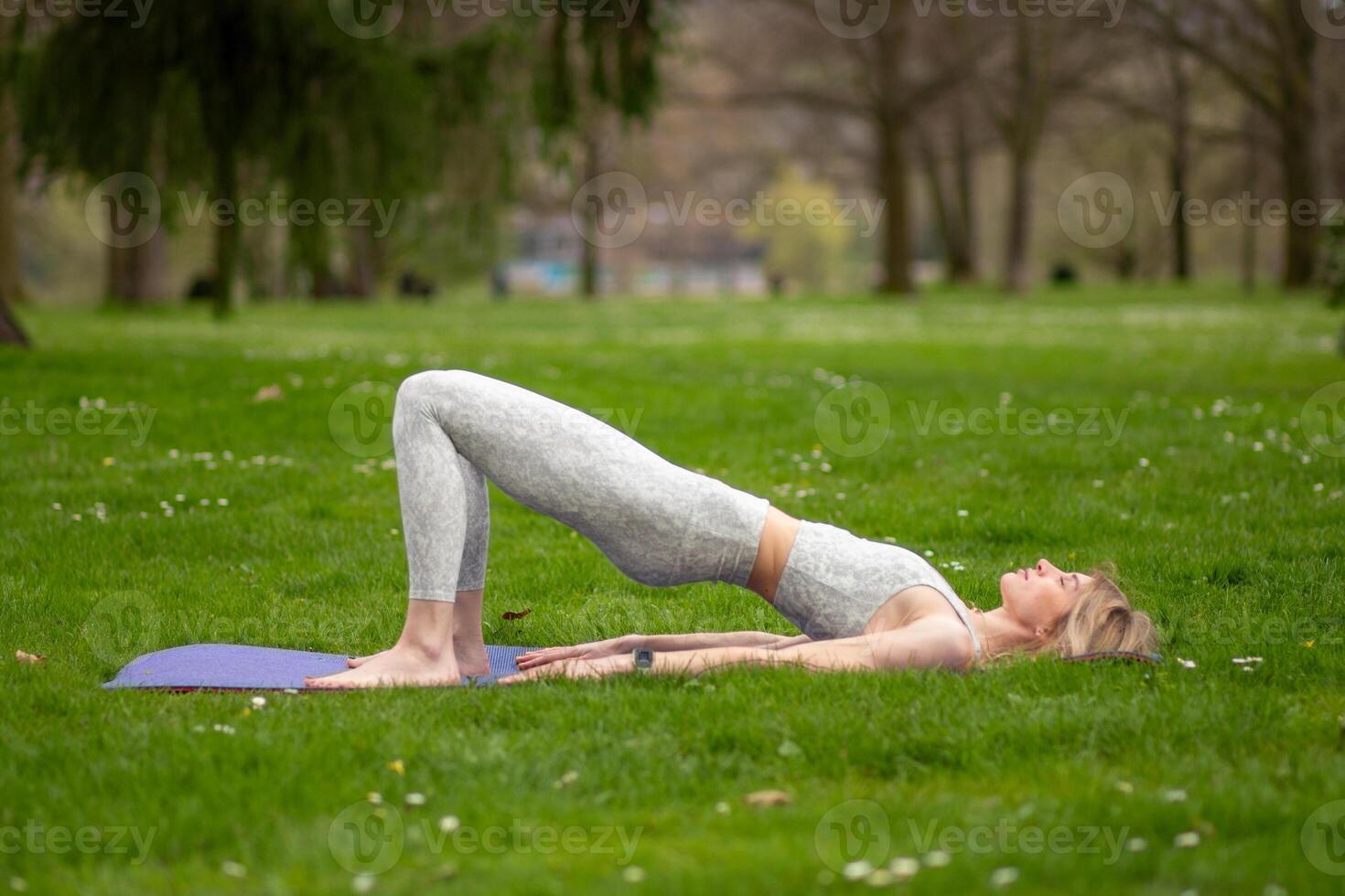 Woman performing bridge pose outdoors photo
