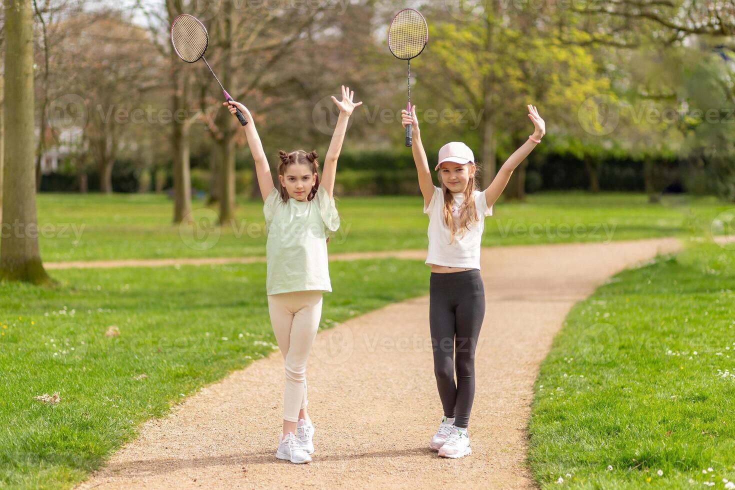 Two girls posing with badminton rackets in the park photo