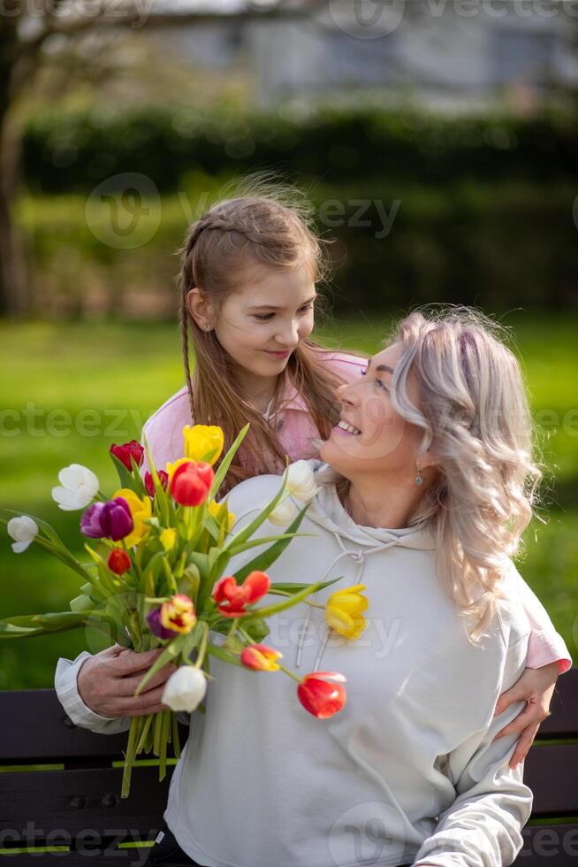 Daughter gives mother tulips, both smiling outdoors photo