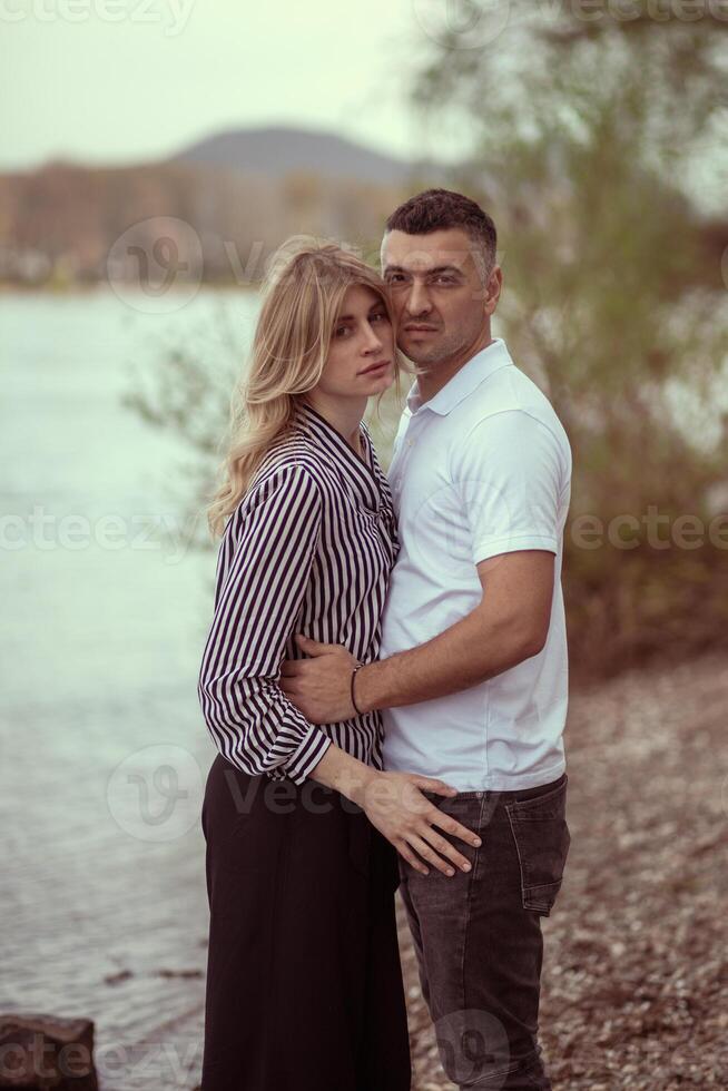 Couple standing by the river, man hugging woman. photo