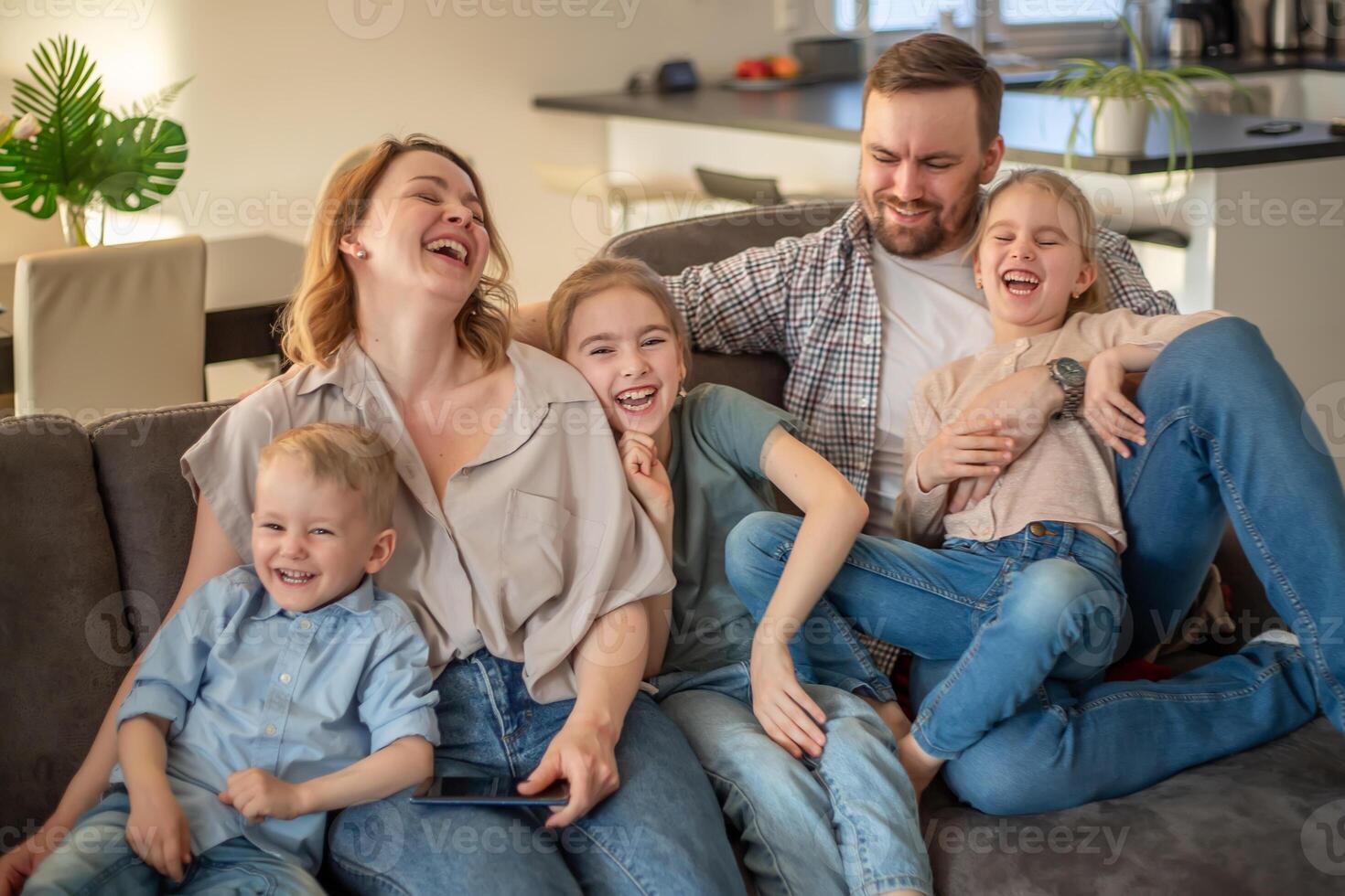 family portrait. family photo in which mom, dad, daughters, son and dog are smiling and hugging on the couch in a cozy homely atmosphere