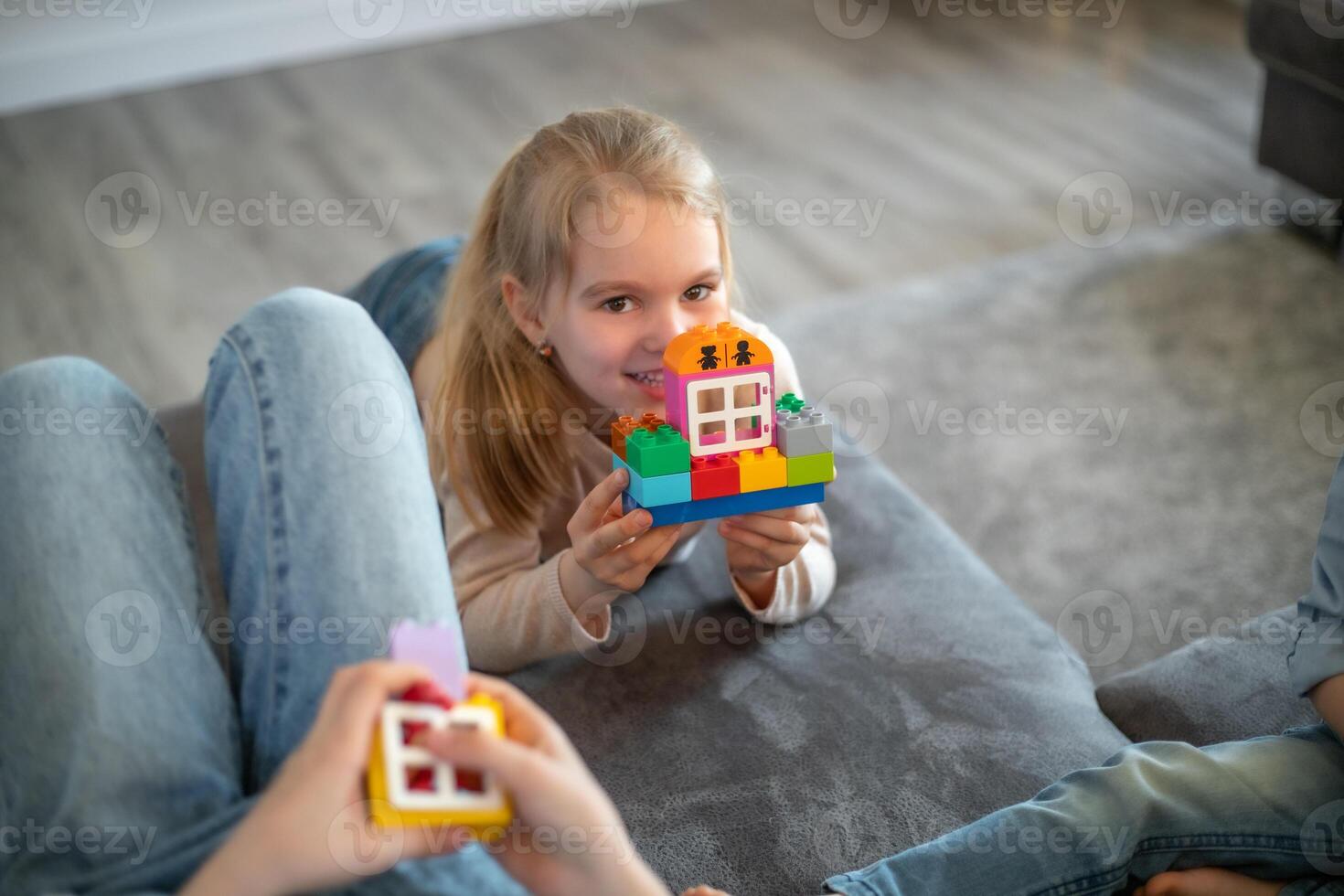 kids are playing with blocks. The boy sits on the sofa and builds a house from the constructor photo