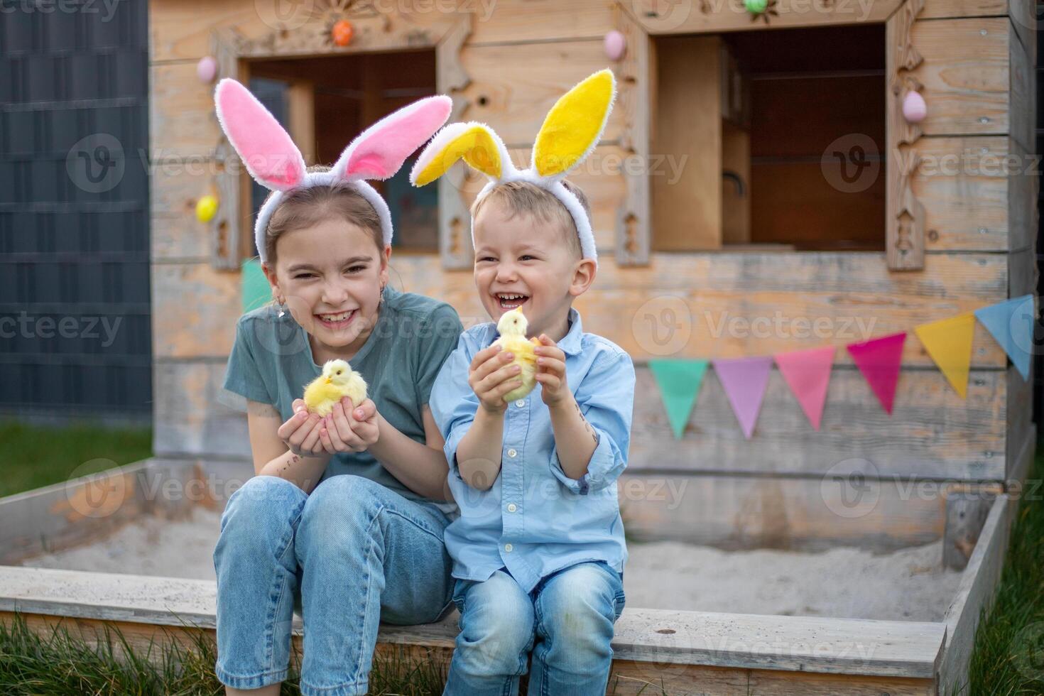 brother and sister in bunny ears celebrate easter. children play with chickens. Happy easter photo