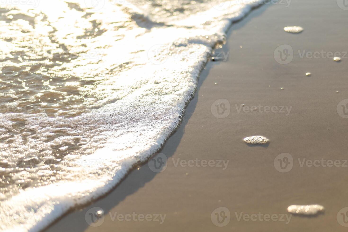 Gentle waves lap against a sunlit beach, capturing moments of tranquility at golden hour by the shoreline photo