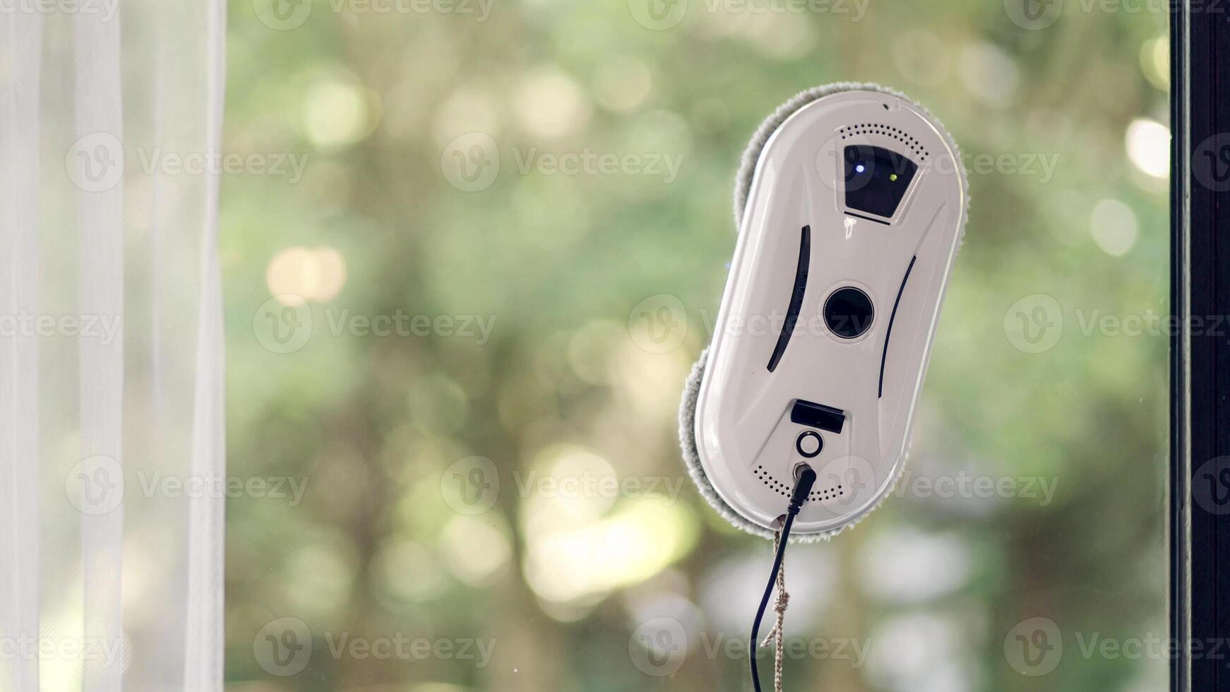 Side view of window cleaning robot on glass with light shadows. photo