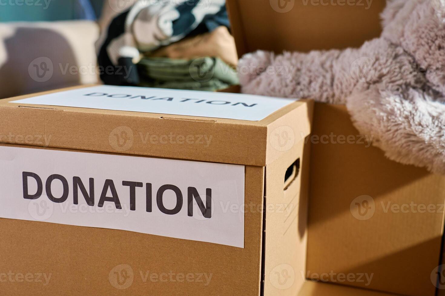 Donation boxes in living room. Packed cardboard boxes full of clothes and toys on couch. Concept of charity, social care and volunteering photo