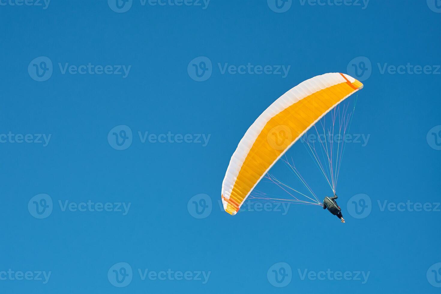 Paraglider flying under clear blue sky photo