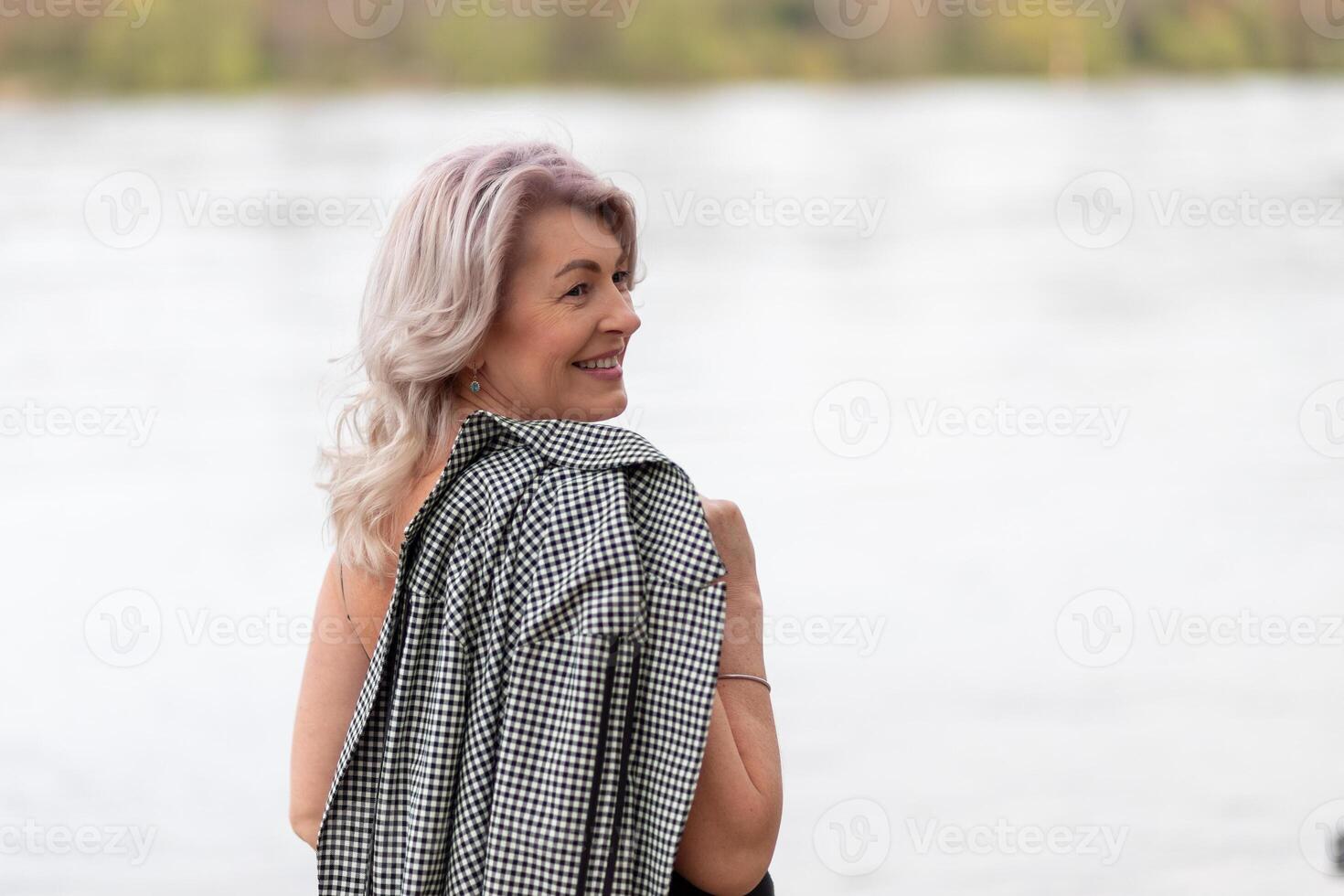 Mature woman turned around by the river photo