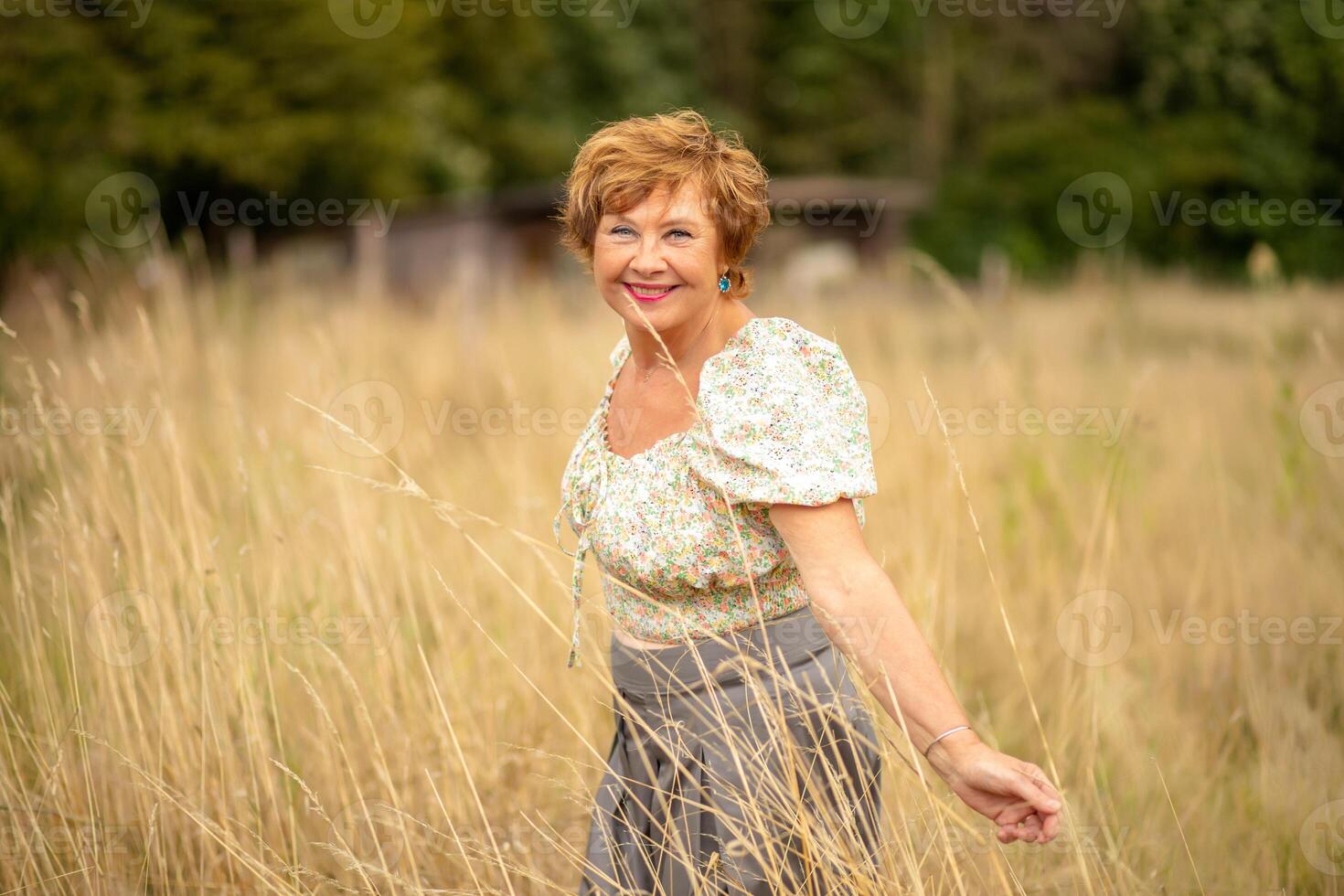 A woman joyfully poses in a sunlit field of tall grass during a warm summer day photo