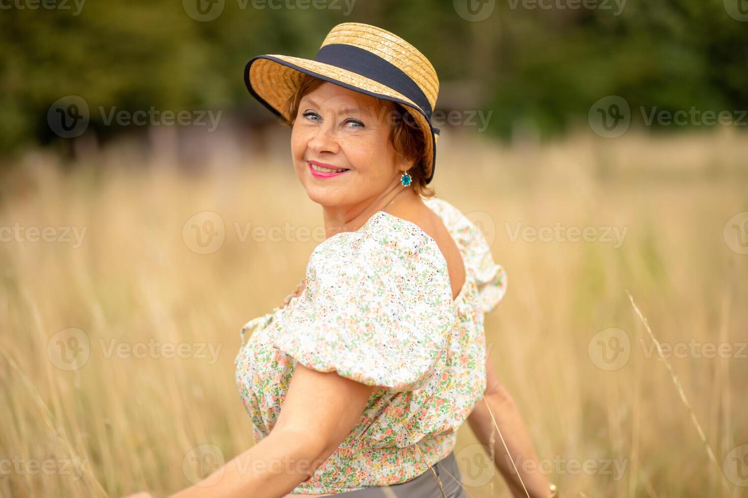 Woman in a straw hat enjoying a sunny day in a field of golden grass photo