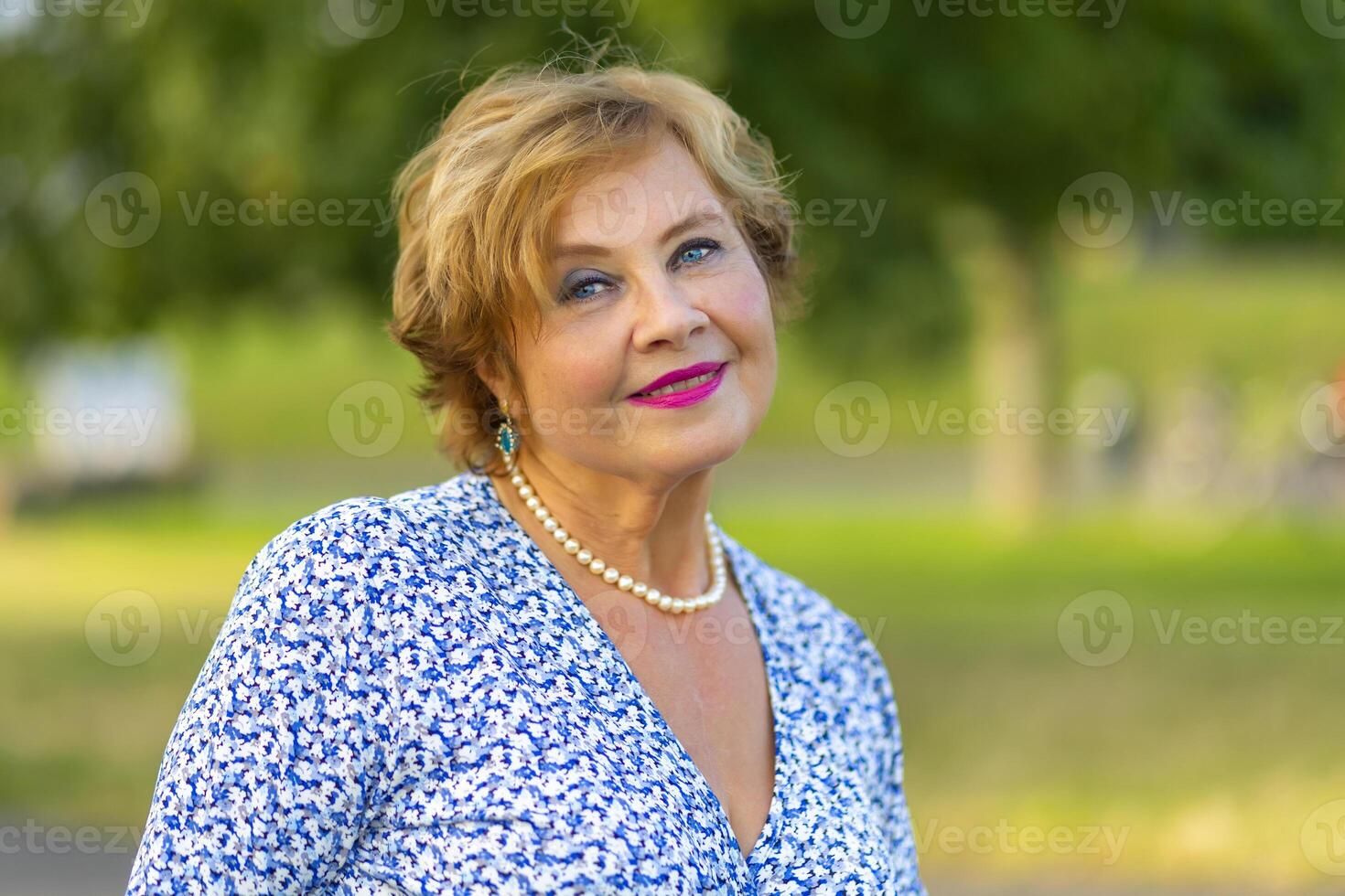 Woman with short blonde hair wearing a blue floral dress poses photo