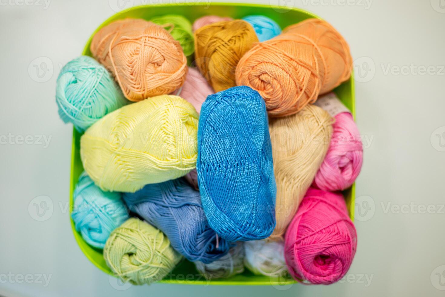 Multi-colored bright yarn lies in a box on a white table, selective focus photo