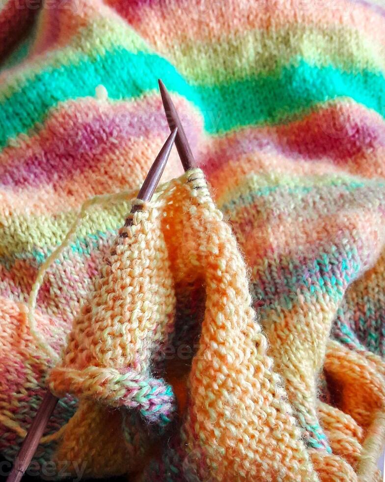 Bright and cozy photo of hand knitting in progress using multicolored yarn and wooden needles. Ideal for DIY, crafting, textile design, and handmade lifestyle visuals.