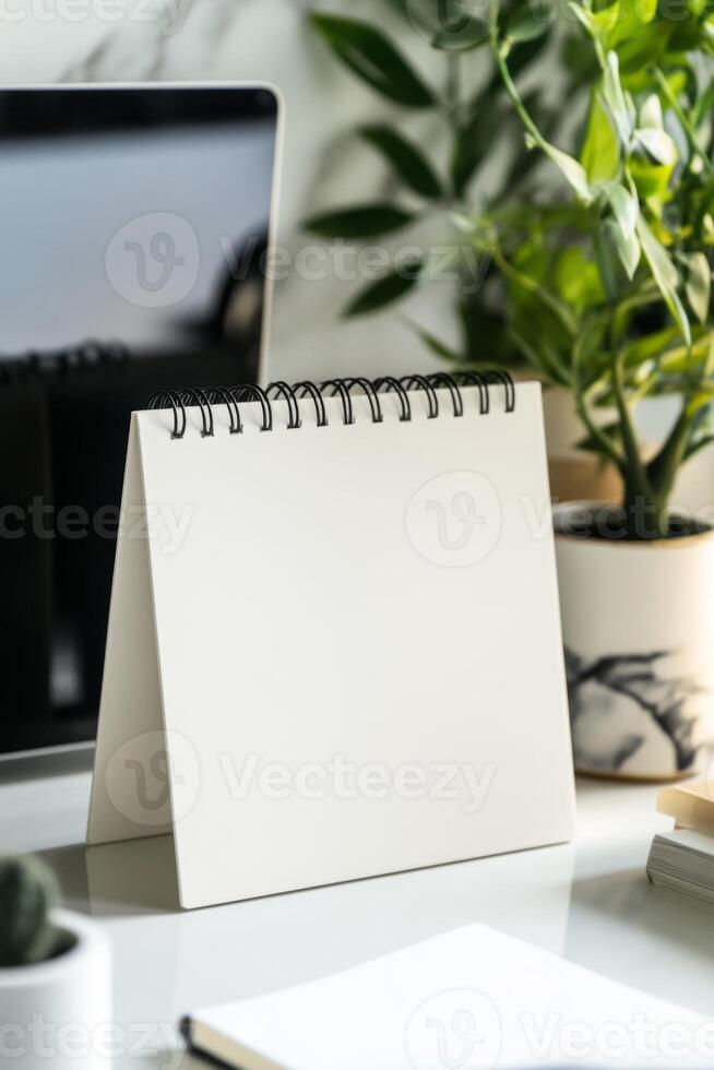 Desk setup with blank notepad and green plants in a modern workspace during the daytime photo