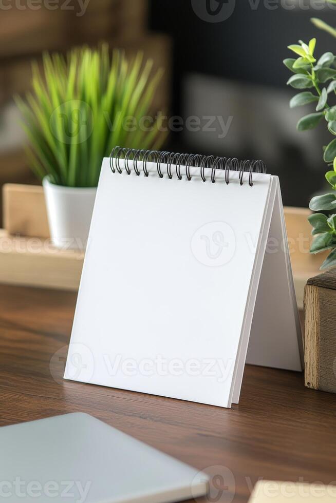 Blank spiral notebook on a wooden desk surrounded by plants during daytime at a cozy workspace photo