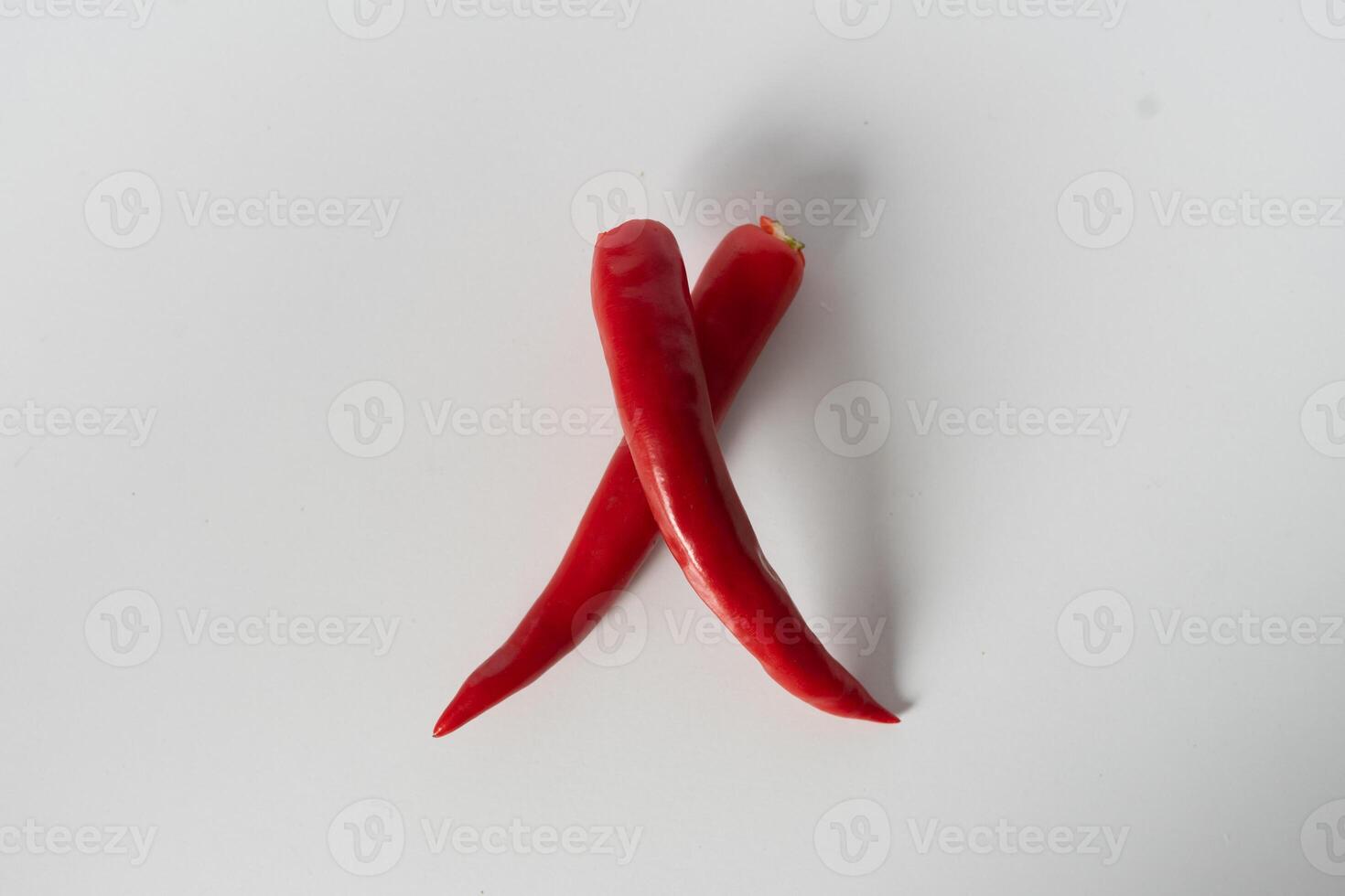 Crossed red chili peppers on white background, vibrant culinary spice photo