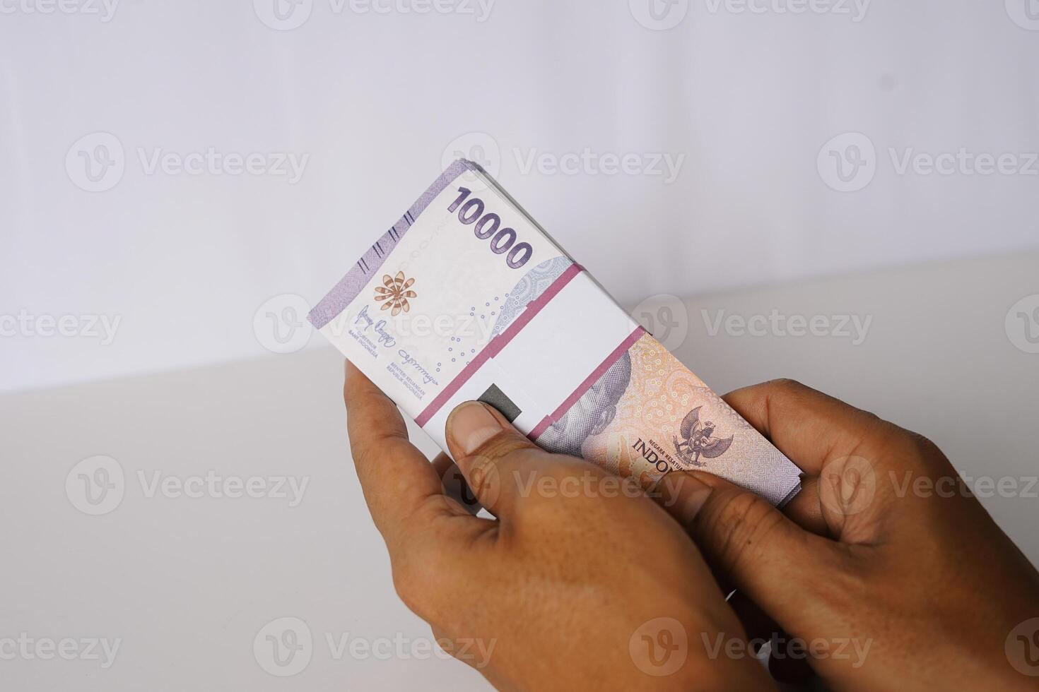 Holding Indonesian Rupiah Banknotes Denomination Ten Thousand on Hand photo