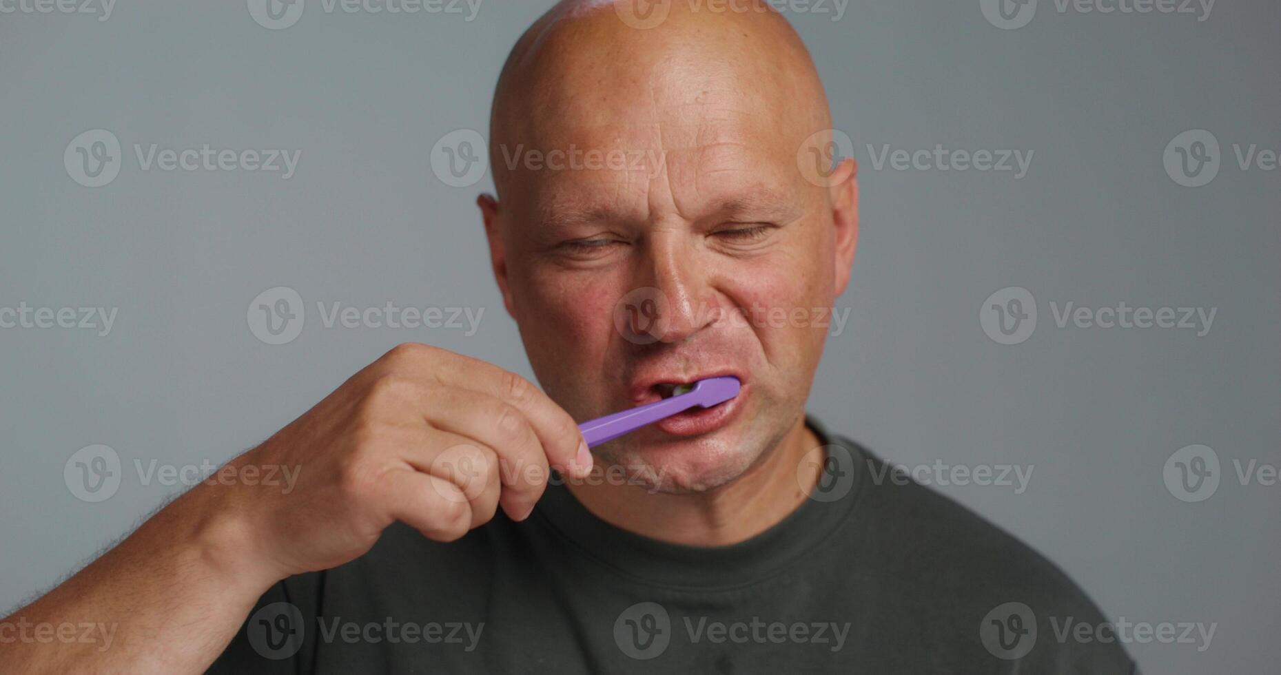 A bald man brushing his teeth photo