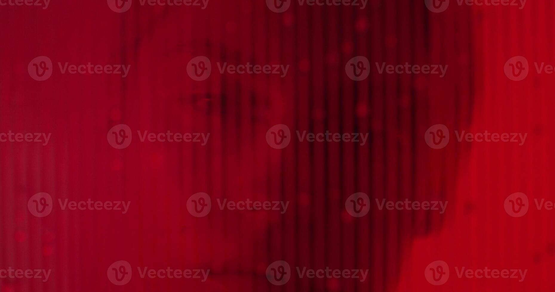 A man is looking into the camera through a red background photo