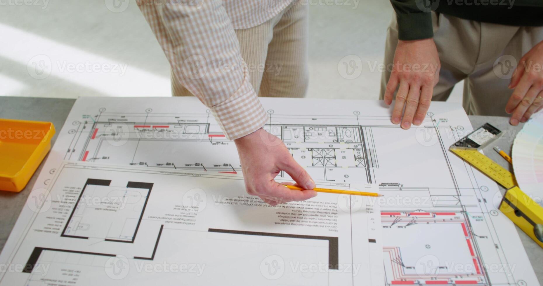 Two people are working on a blueprint with a ruler photo