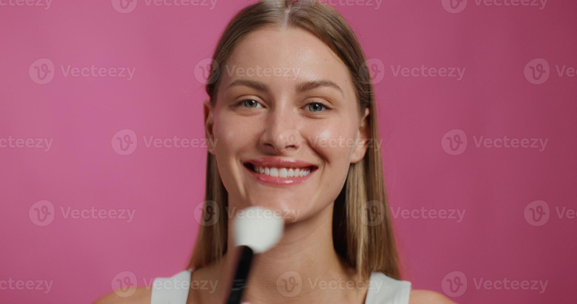 A woman is smiling while brushing her teeth photo