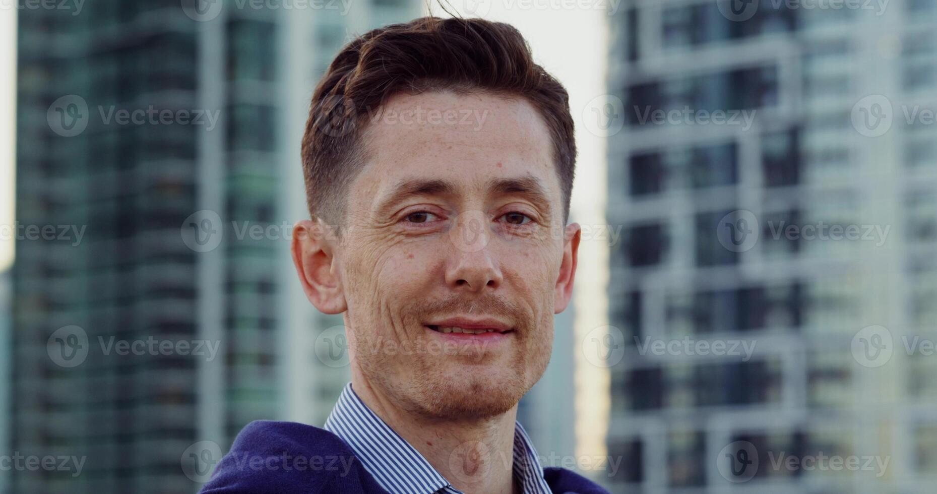 A man in a blue shirt and jacket standing in front of tall buildings photo