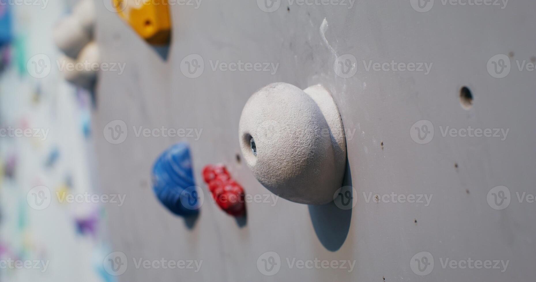 Man climbs the climbing wall, grabbing the artificial ledges imitating stones photo